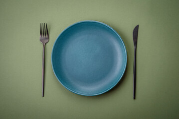 Empty round ceramic plate on a plain background, flatley with copy space