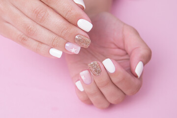 
Beautiful female hands with romantic manicure nails, white and pink gel polish with golden glitter

