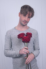 handsome attractive model male boyfriend with romantic gesture  red rose flowers on valentine's day. passionate secretive expression captures feeling for significant other on special occasion 