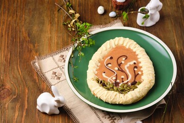 Mazurek, Polish Easter sweet made from shortcrust pastry in the shape of an egg with Easter decoration on a green plate on a wooden background. Polish cuisine. - obrazy, fototapety, plakaty