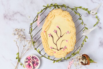 Mazurek, a Polish Easter sweet made from shortcrust pastry in the shape of an egg with Easter decoration on a metal lattice on a light background. Polish cuisine.