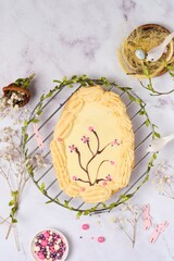 Mazurek, a Polish Easter sweet made from shortcrust pastry in the shape of an egg with Easter decoration on a metal lattice on a light background. Polish cuisine. - obrazy, fototapety, plakaty