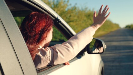 girl rides car with her hand out window, young happy carefree woman, girl sits car looks out window...
