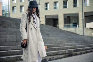 young woman with hat and coat going down stairs