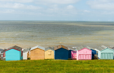 Fototapeta na wymiar Colorful holiday beach huts homes facing the calm blue sea.