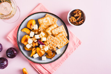 Dinner for girls, cheese, biscuits, plums on a plate and a glass of wine on the table top view
