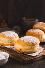 Sweet donuts with powdered sugar filled with boiled condensed milk on a plate vertical view