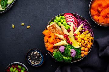 Vegan buddha bowl with sweet potato, quinoa, chickpeas, edamame, tofu, corn, radish, broccoli and...