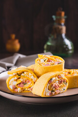 Tortilla rolls with salad of sausages, eggs, cheese and herbs on a plate vertical view