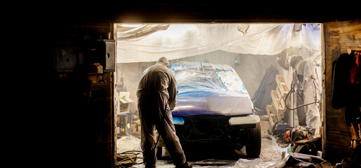 Master car painter paints a car with a spray gun. Car painting at home.
