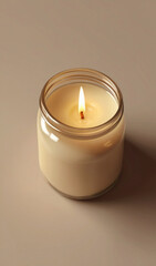 Hermosa Vela encendida en un frasco de vidrio en un fondo en tonos crema. Detalle para invitaciones, celebraciones, decoracion, religion.