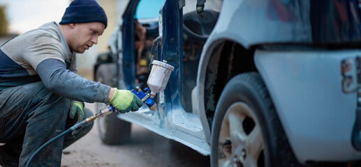 Master car painter paints a car with a spray gun. Car painting at home.