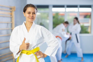 Young girl in kimono with obi belt posing for photos in gym