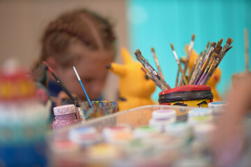 Girls 4-5 years old are sitting at a table and painting with colorful paints. Children's...