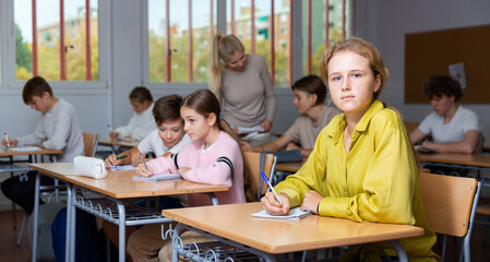 Portrait of smiling positive schoolgirl posing in classroom during lesson in secondary school