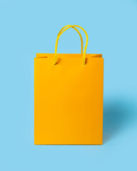 Yellow paper shopping bag on blue background. Shopping sale delivery concept. Packaging gift.