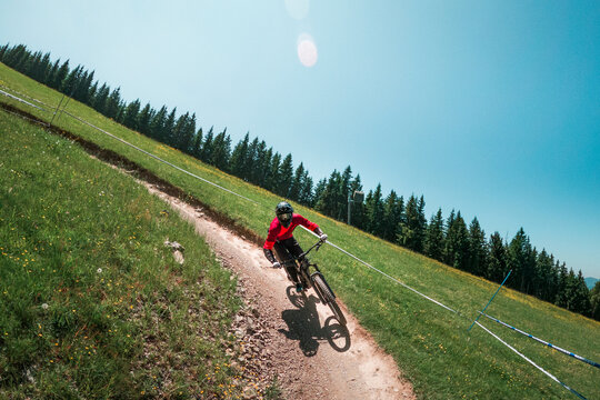 Downhill mountain biking on a shaped bike park trail in Austria, sunny blue sky day, bike leaning in the curve.