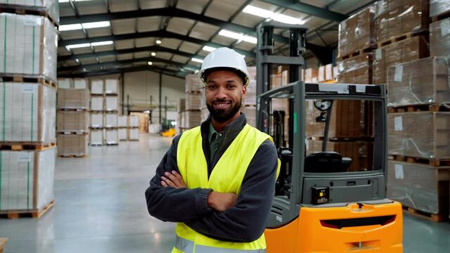 Male warehouse worker standing by forklift. Warehouse manager checking delivery, stock in warehouse, inspecting products for shipment.