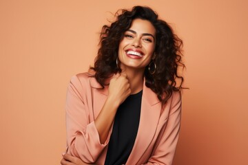 Portrait of a happy young woman with long curly hair, wearing a pink jacket and black skirt.
