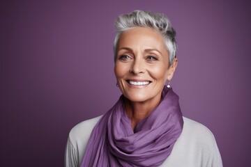 Portrait of a happy senior woman with purple scarf over purple background