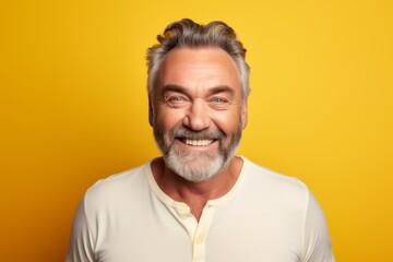 Portrait of a happy senior man looking at camera over yellow background
