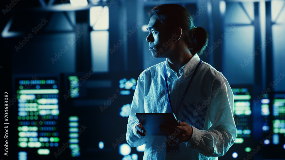 Poster asian employee walking through data center equipment clusters providing processing resources for dif