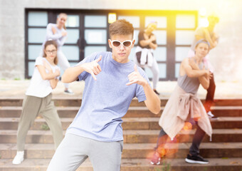 Naklejka premium Happy smiling teenagers practicing vigorous hip hop movements at city street
