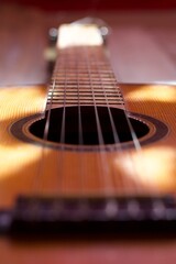 photograph of the neck of an acoustic guitar, strings, soundboard and frets