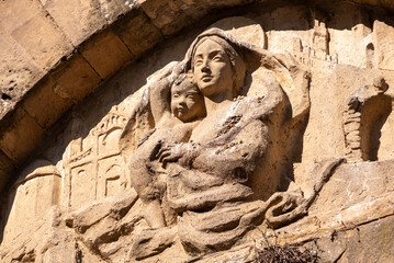 Fototapeta na wymiar An old baroque engraved sculpture of Mary and Jesus over an entrance to the Cappella della Croce di Giorno in Volterra