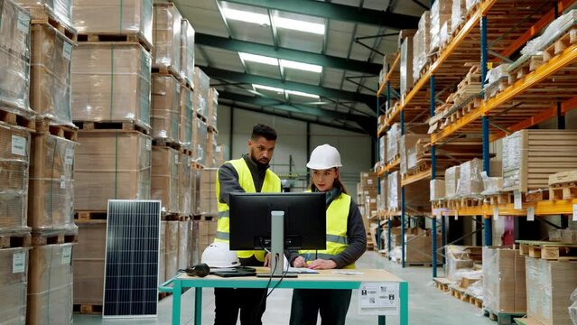 Warehouse manager talking with logistics employee in warehouse, planning transport of products, talking shipping process.