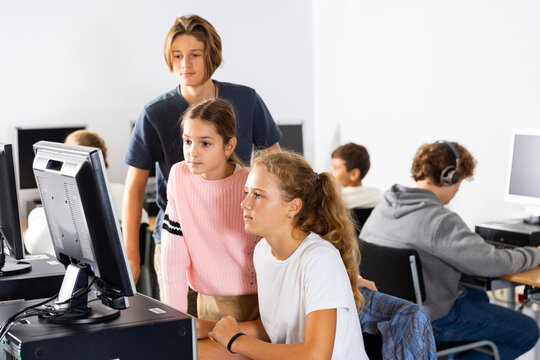 Students help each other solve problems on the computer in the classroom
