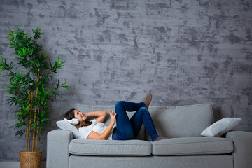Photo with copy space of a woman lying on the sofa listening to music