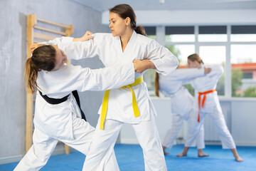 Obraz premium Pairs classes in judo or jiu-jitsu - two teenage girls practice grabbing and throwing on sports mats