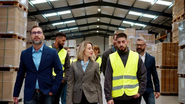 Full team of warehouse employees walking in warehouse. Team of workers, managers, female director in modern industrial factory, heavy industry, manufactrury.