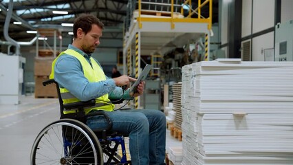 Man in wheelchair working in industrial factory, in adjustable workstation. Concept of workers with disabilities, accessible workplace for employees with mobility impairment.