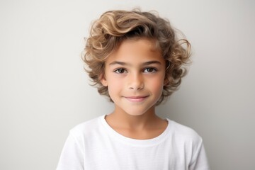 Portrait of a cute little boy with curly hair on a gray background - obrazy, fototapety, plakaty