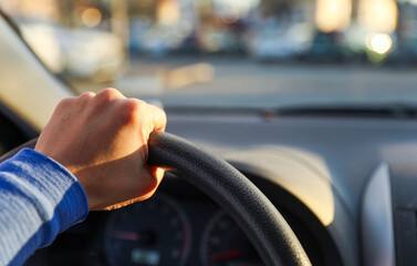 hand gripping a steering wheel while driving a car, focused and in control