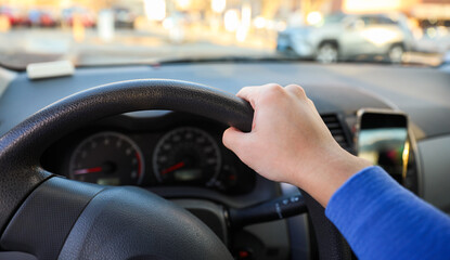 hand gripping a steering wheel while driving a car, focused and in control