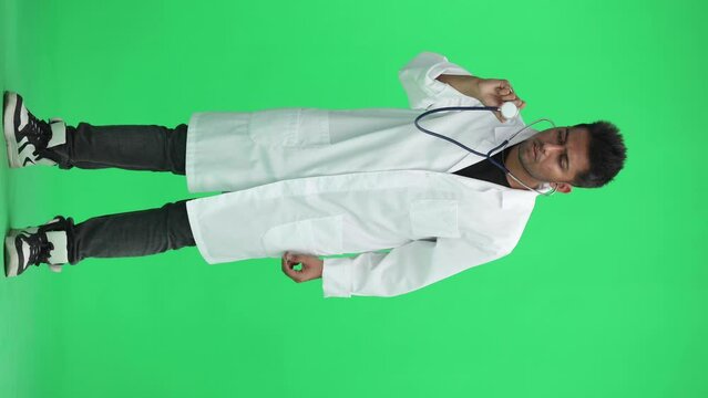 male doctor on a green background. holding a statoscope at full height