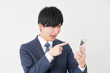 スマートフォンを見て怒るビジネスマン　白背景