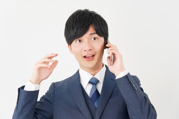スマートフォンで通話して驚くビジネスマン　白背景