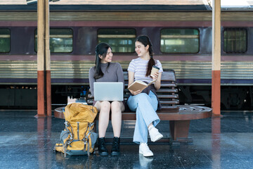 Fototapeta premium Woman traveler with backpack using laptop to planning vacation on holiday relaxation at the train station