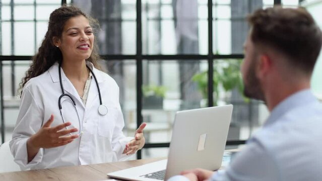 Doctor talking to patient in office, taking notes, smiling