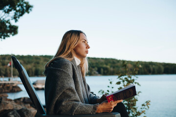 Woman enjoying the moment of reading a book at sunset in the park.
Blonde woman looking at a book and thinking.