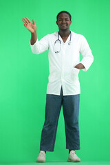 Full-length male doctor waving his hand on a green background