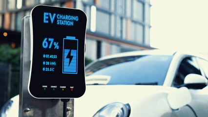 EV charging station display battery status interface for electric car, exemplifying green city with...
