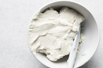 Top view of cream buttercream in a white mixing bowl, silky smooth american buttercream in a ceramic bowl, overhead view of smooth buttercream