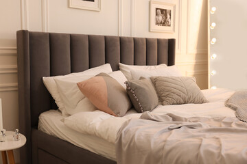 Large comfortable bed with soft pillows and blanket in room. Home textile