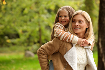 Fototapeta premium Happy mother walking with her daughter in autumn park, space for text