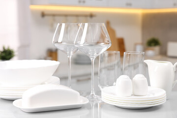 Set of clean dishware and glasses on table in kitchen